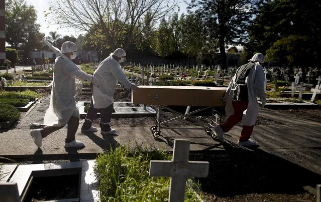 Cemetery workers push the coffin of a COVID-19 victim at a cemetery in Buenos Aires, Argentina, Saturday, May 8, 2021. Argentina has so far reported more than 67,300 confirmed deaths and more than 3.1 million people sickened by the disease. (Photo by Natacha Pisarenko/AP Photo)