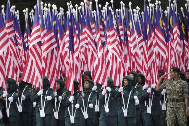 Members of Malaysian school-based government youth organization KRS hold their national flags during the National Day parade in Putrajaya, Malaysia, Thursday, August 31, 2023. Prime Minister Anwar Ibrahim urged Malaysians to unite and reject racial and religious bigotry, as the country marked its 66th year of freedom from British rule on Thursday with fireworks and a street parade. (Photo by Vincent Thian/AP Photo)