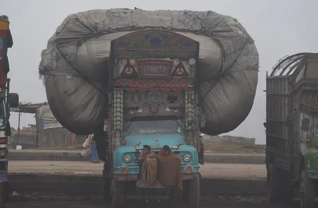 Pakistani drivers sit on a truck during a foggy day at the roadside in Lahore on January 15, 2016. The ongoing spell of dense fog and freezing weather conditions has continued to disturb the scheduled arrival and departure of flights and trains in Pakistan's Punjab province. (Photo by Arif Ali/AFP Photo)