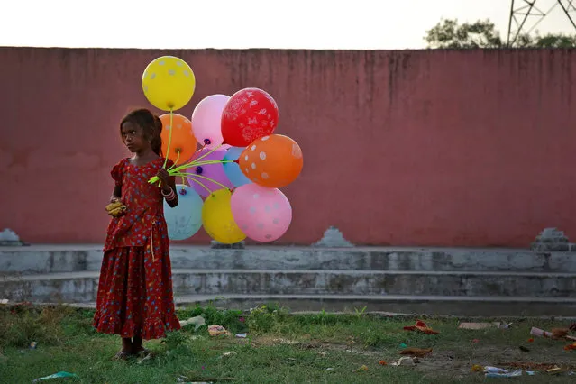 A young girl sells balloons by the Yamuna River on the last day of the ten-day-long Ganesh Chaturthi festival in Delhi, September 15, 2016. (Photo by Cathal McNaughton/Reuters)