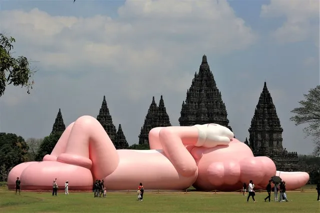 People look at an art installation created by American artist Brian Donnelly, also known as Kaws, at the Prambanan Temple, one of the largest Hindu temples in Southeast Asia and a UNESCO World Heritage, in Yogyakarta on August 19, 2023. (Photo by Devi Rahman/AFP Photo)