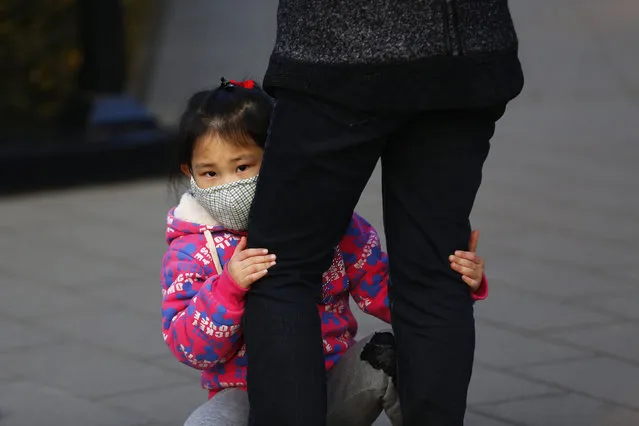 A Chinese girl wears a mask at Jingshan Park during the haze day in Beijing, China, 19 December 2016. Serious air pollution hit in China's nine provinces and cities, with haze hanging over an area of about 1.42 million square kilometers on 18 December. The air pollution alert lasts in many part of China that the heavy pollution is expected to persist over 11 provinces and cities on 19 December 2016. (Photo by Wu Hong/EPA)