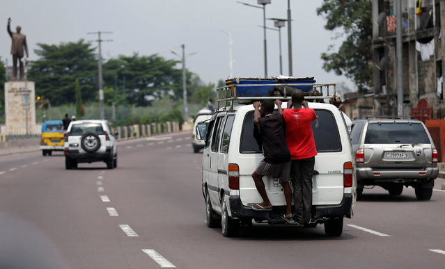 Men ride holding onto the back of a public transport mini-van along the highway in the Democratic Republic of Congo's capital Kinshasa, December 21, 2016. (Photo by Thomas Mukoya/Reuters)