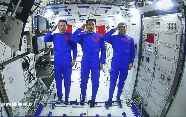 In this photo released by China's Xinhua News Agency, Chinese astronauts, from left; Tang Hongbo, Nie Haisheng, and Liu Boming salute from aboard China's space station core module Tianhe during a video conversation with Chinese President Xi Jinping, Wednesday, June 23, 2021. (Photo by Yue Yuewei/Xinhua via AP Photo)