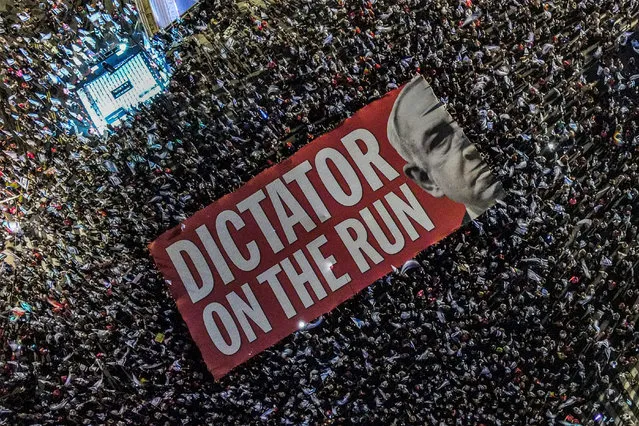 This aerial view shows demonstrators unfurling a giant banner against Israeli Prime Minister Benjamin Netanyahu during a rally against the Israeli government's judicial overhaul plan near Azrieli Mall in Tel Aviv on September 23, 2023. (Photo by Jack Guez/AFP Photo)