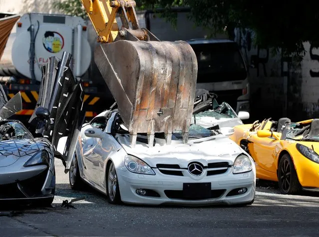 A backhoe destroys smuggled luxury cars at the Bureau of Customs in Manila, Philippines, 18 June 2021. The destruction of the vehicles is done to warn smugglers to pay the correct importation tax or have their cars seized by the government and be destroyed. (Photo by Francis R. Malasig/EPA/EFE)