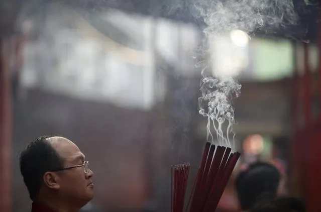 A man waits to plant joss sticks at Dharma Bhakti Temple on the first day of the  Lunar New Year in Jakarta, Indonesia February 8, 2016. (Photo by Darren Whiteside/Reuters)