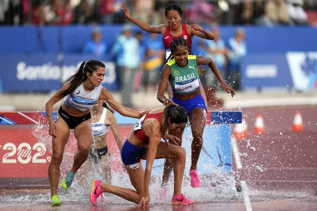 Argentina's Clara Baiocchi pats Puerto Rico's Alondra Negron as she falls during the women's 3000-meters steeplechase final at the Pan American Games in Santiago, Chile, Saturday, November 4, 2023. (Photo by Fernando Vergara/AP Photo)