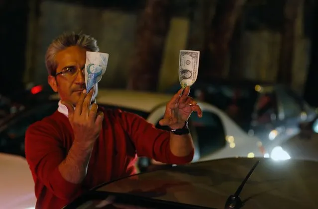 An Iranian man holds a one thousand Iranian Rial (L) and a one US dollar (R) as he celebrates in the streets of Tehran, Iran, 02 April 2015, after nuclear talks between Iran and World powers ended in Lausanne, Switzerland. Iran and six world powers have agreed on the key points of a deal over Iran's controversial nuclear programme. Iranians were so happy by hearing that world powers are ready to lift the sanctions against the country. (Photo by Abedin Taherkenareh/EPA)