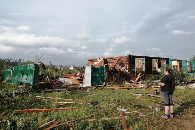 A woman stands by a ruined house in Tver Region, Russia on August 3, 2021. Yesterday evening a thunderstorm with a fierce wind of up to 25 m/s hit the Tver Region affecting the town of Andreapol and the Ostashkovsky Municipal District, killing 3 people and injuring 8. Power lines and 65 houses have been damaged. (Photo by Nash Put Newspaper of the Velikoluksky District/TASS)