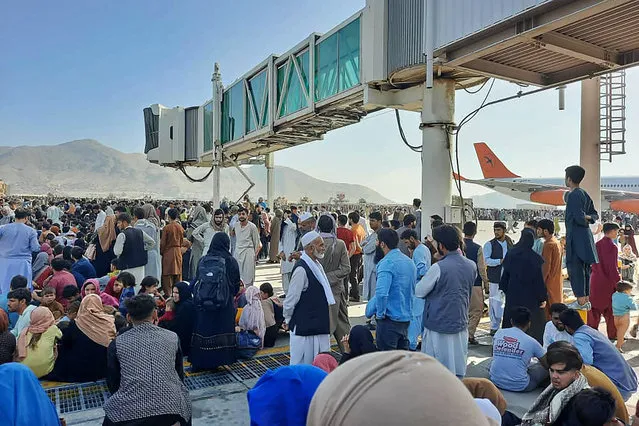 Afghans crowd the tarmac of the Kabul airport on August 16, 2021, to flee the country as the Taliban were in control of Afghanistan after President Ashraf Ghani fled the country and conceded the insurgents had won the 20-year war. (Photo by AFP Photo/Getty Images)
