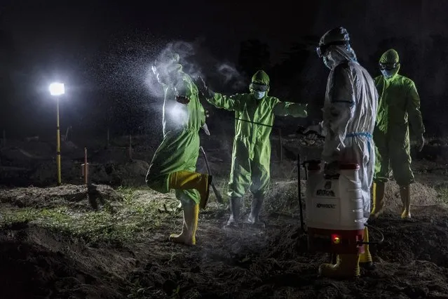 A worker is sprayed with disinfectant after conduct a burial the body of a baby that died in the womb after the mother contracted Covid-19 during a funeral at the cemetery on August 09, 2021 in Yogyakarta, Indonesia. Indonesia, facing a severe wave of Covid-19 infections, has passed the grim milestone of more than 100,000 deaths recorded due to the disease. Television news channels quoted pediatricians who said that one in eight of those infected are children, as concerns grow about the unvaccinated demographic's ability to fend off the delta variant. (Photo by Ulet Ifansasti/Getty Images)