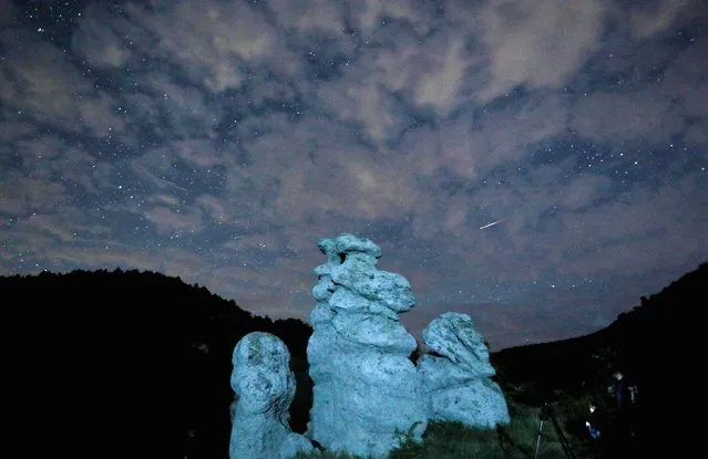 A meteor streaks during the Perseid meteor shower in the night sky over the village of Kuklici, known for its hundreds of naturally formed stones which resemble human beings, near Kratovo, North Macedonia on August 13, 2023. (Photo by Ognen Teofilovski/Reuters)