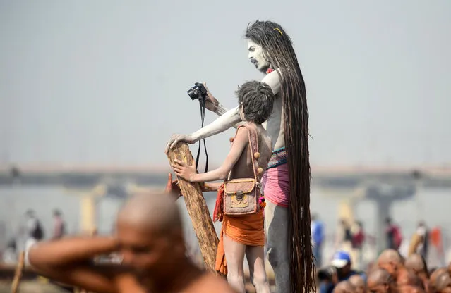 Indian “Naga Sadhus” (Hindu holy men) take photos as newly-initiated “Naga Sadhus” perform rituals on the banks of the Ganges River during the Kumbh Mela festival, in Allahabad on February 1, 2019. During every Kumbh Mela, the diksha, a ritual of initiation by a guru takes place for new members. (Photo by Sanjay Kanojia/AFP Photo)