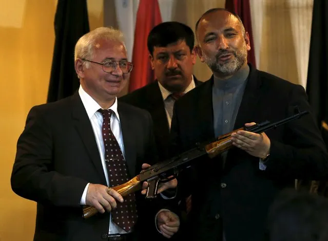 Russia's ambassador, to Afghanistan Alexander Mantytskiy (L) hands over an AK-47 to Afghan national security adviser Hanif Atmar (R) after a conference at the International Kabul Airport, Afghanistan February 24, 2016. Afghan officials took delivery of 10,000 automatic rifles and millions of rounds of ammunition as a gift from Russia on Wednesday, another sign of deepening involvement by Moscow in the war-torn country. (Photo by Mohammad Ismail/Reuters)