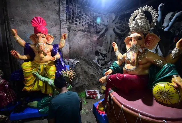 An artist gives finishing touches to an idol of the elephant-headed Hindu God Ganesha at a workshop ahead of the Ganesh Chaturthi festival in Allahabad on September 7, 2021. (Photo by Sanjay Kanojia/AFP Photo)