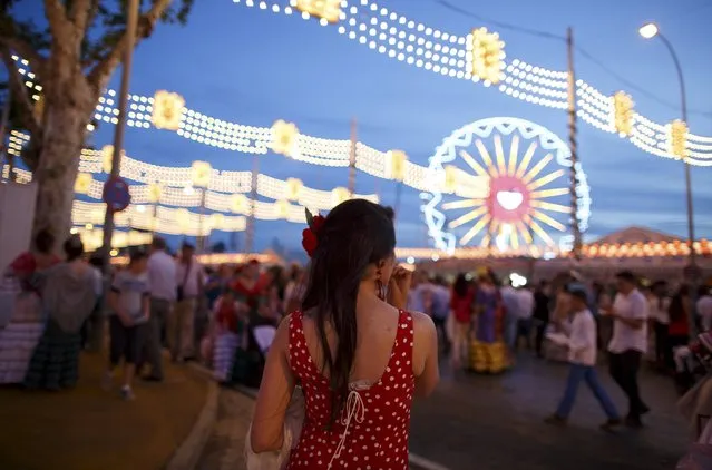 A woman wearing a sevillana dress waits for someone during the traditional Feria de Abril (April fair) in the Andalusian capital of Seville, southern Spain, April 23, 2015. (Photo by Marcelo del Pozo/Reuters)