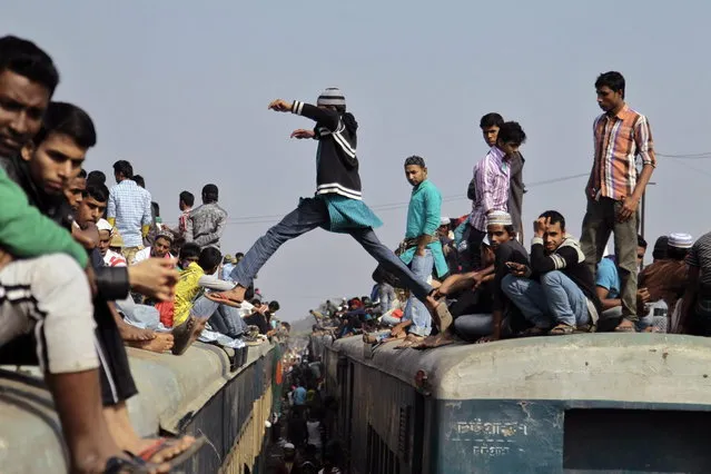 A man jumps from the top of one overcrowded train to another as thousands of Bangladeshi Muslims try to return home after attending three-day Islamic Congregation on the banks of the River Turag in Tongi, 20 kilometers (13 miles) north of the capital Dhaka, Bangladesh, Sunday, January 26, 2014. (Photo by A. M. Ahad/AP Photo)