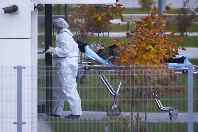 A medical worker carries a patient suspected of having coronavirus on a stretcher at a hospital in Kommunarka, outside Moscow, Russia, Saturday, October 16, 2021. Russia's daily death toll from COVID-19 has exceeded 1000 for the first time as the country faces a sustained wave of rising infections. (Photo by Alexander Zemlianichenko/AP Photo)