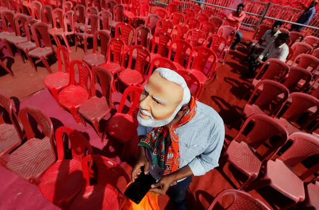 A supporter of India's ruling Bharatiya Janata Party (BJP) wearing a mask of Prime Minister Narendra Modi checks his mobile phone as he attends an election campaign rally being addressed by Modi in Meerut in the northern Indian state of Uttar Pradesh, India, March 28, 2019. (Photo by Adnan Abidi/Reuters)