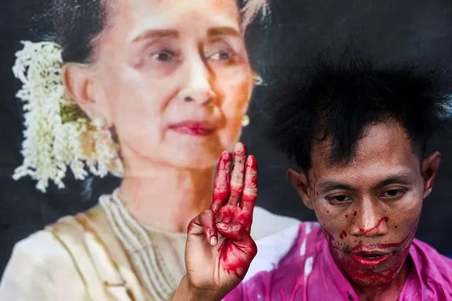 A protester with fake blood on his body raises a three-finger salute in a demonstration to mark the third anniversary of Myanmar’s 2021 military coup, outside of the United Nations office in Bangkok, Thailand on February 1, 2023. (Photo by Chalinee Thirasupa/Reuters)