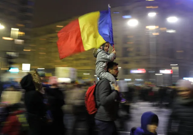 Young kid carries Romanian national flag during a demonstration in Bucharest, Romania, Sunday, February 5, 2017. Romania's government met Sunday to repeal an emergency decree that decriminalizes official misconduct, a law that has prompted massive protests at home and widespread condemnation from abroad. (Photo by Vadim Ghirda/AP Photo)