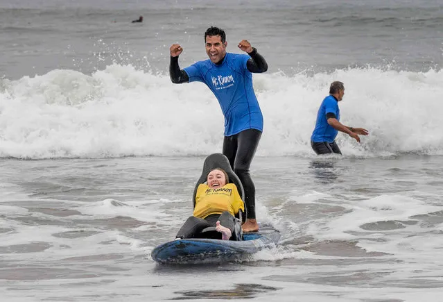 Emily Rowley, 20, takes a ride on a 15-foot chair board designed for adaptive surfing in Huntington Beach, Calif. on Friday, October 22, 2021. The board was developed by Rocky McKinnon, who runs McKinnon Surf & SUP Lessons. (Photo by Paul Bersebach/The Orange County Register via AP Photo)