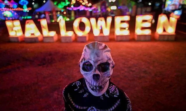 A person wears a skeleton mask during a show at River View Park in Cali, Colombia, on October 29, 2021, ahead of Halloween. (Photo by Luis Robayo/AFP Photo)