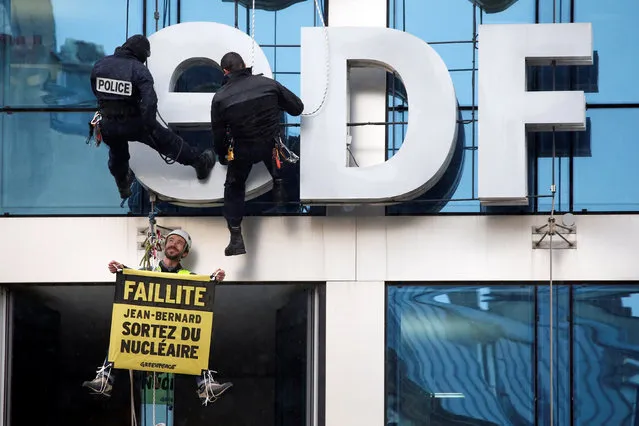 Police rappel to move a Greenpeace activist holding a sign that reads, “Bankrupcy, Jean- Bernard, out of the nuclear” as the presentation of the state- controlled energy giant EDF group's 2016 results were being announced inside, on February 14, 2017 in the French capital Paris. (Photo by Charles Platiau/Reuters)