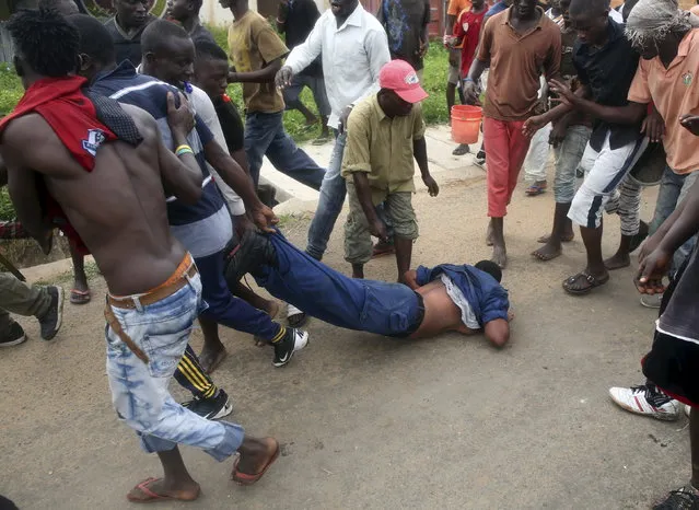 A mob drags a female police officer accused of shooting a protester in the Buterere neighborhood of Bujumbura, Burundi, May 12, 2015. (Photo by Goran Tomasevic/Reuters)