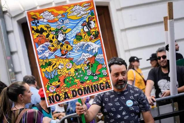 An environmental activist holds a sign that reads in Spanish “No to Dominga” outside the Environment Ministry to show support for their Committee of Ministers' decision to unanimously reject the Dominga mining project in Santiago, Chile, Wednesday, January 18, 2023. The project by Andes Iron had been proposed in La Higuera, in the Coquimbo region. (Photo by Matias Delacroix/AP Photo)