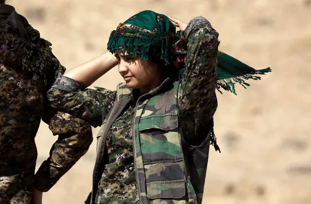 A female Kurdish fighter and member of the US-backed Syrian Democratic Forces (SDF), made up of an alliance of Arab and Kurdish fighters, adjusts her head scarf in the village of Sabah al-Khayr on the northern outskirts of Deir Ezzor as they advance to encircle the Islamic State (IS) group bastion of Raqa on February 21, 2017. The SDF made a major incursion into the oil-rich province of Deir Ezzor as part of their push for Raqa, field commander Dejwar Khabat said. (Photo by Delil Souleiman/AFP Photo)