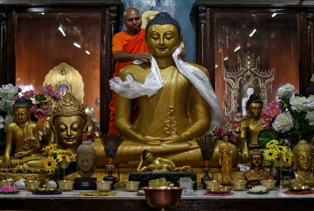 A Buddhist monk offers a khada, traditional ceremonial scarf, on a statue of Lord Buddha inside a temple ahead of the Buddha Purnima festival, also known as Vesak Day, in Kolkata, India May 17, 2019. (Photo by Rupak De Chowdhuri/Reuters)