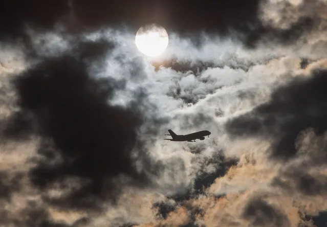 A plane flies through the morning sky past the sun hidden behind clouds on February 11, 2016 in Frankfurt am Main, western Germany. (Photo by Frank Rumpenhorst/AFP Photo/DPA)