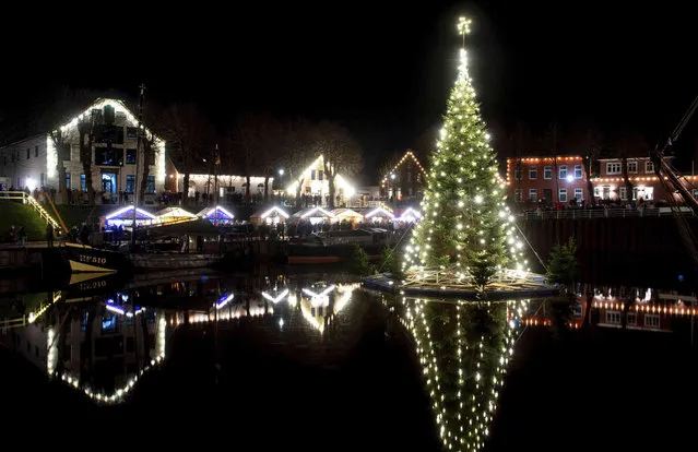 The floating Christmas tree lights up in the historic harbour of the village of Carolinensiel, Germany, Saturday, November 27, 2021. (Photo by Hauke-Christian Dittrich/dpa via AP Photo)
