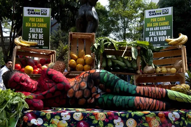 An activist of AnimaNaturalis performs over a table with fruits and vegetables protesting against meat consumption, on the World Day Without Meat, in Mexico City, on March 20, 2014. (Photo by Yuri Cortez/AFP Photo)