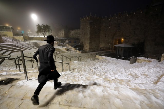 An Ultra Orthodox Jewish man walks into Jerusalem's Old city via Damascus gate during a snowy day in Jerusalem, February 18, 2021. (Photo by Ammar Awad/Reuters)