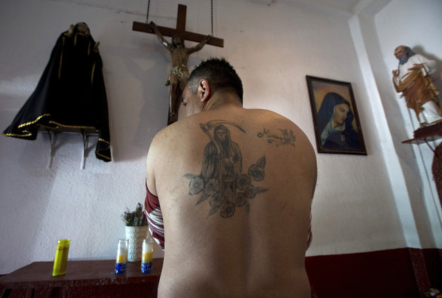 In this February 19, 2017 photo, Death Saint devotee Francisco Rodriguez shows his tattoo of the popular saint inside Mercy Church on the edge of Mexico City's Tepito neighborhood. To devotees, “Santa Muerte” is associated with healing, protection, financial well-being, and ensuring a path to the afterlife. (Photo by Marco Ugarte/AP Photo)
