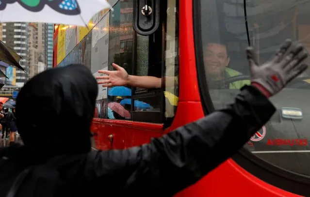 A bus driver shows his support to an anti-extradition bill protester during the march to demand democracy and political reforms, in Hong Kong, China on August 18, 2019. (Photo by Tyrone Siu/Reuters)