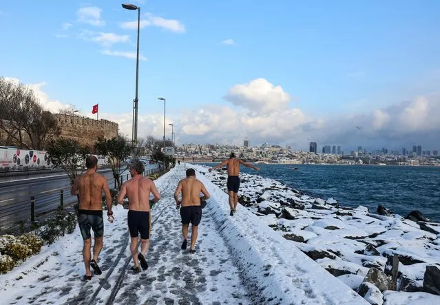 A group of swimmers run to warm-up before they dive into the chilly waters of the Bosphorus during a snowy day in Istanbul, Turkey, January 23, 2022. (Photo by Umit Bektas/Reuters)