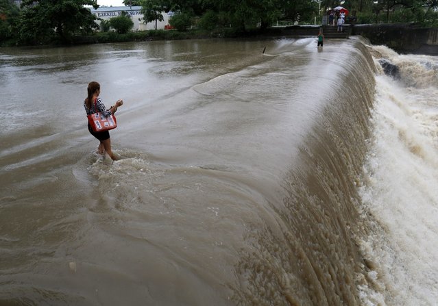 Filipinos cross a swelling river in Las Pinas city, south of Manila, Philippines, 09 July 2015. According to the Philippines State weather forecast, heavy rainfall is expected in Metro Manila and nearby provinces due to an enhanced Southwest Monsoon and Tropical Storm Linfa, Typhoon Chan-hom and Typhoon Nangka which are lining up across the Pacific Ocean. (Photo by Francis R. Malasig/EPA)