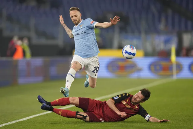 Lazio's Manuel Lazzari challenges for the ball with Venezia's Marco Modolo, on the ground, during the Serie A soccer match between Lazio and Venezia, at Rome's Olympic Stadium, in Rome, Italy, Monday, March 14, 2022. (Photo by Andrew Medichini/AP Photo)