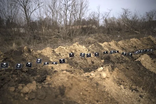 Personalized grave markers line a mass grave at a cemetery in Kharkiv, Ukraine, Saturday, March 26, 2022. According to workers, most of them died of natural causes and were buried in the mass grave after no relatives claimed the bodies. (Photo by Felipe Dana/AP Photo)