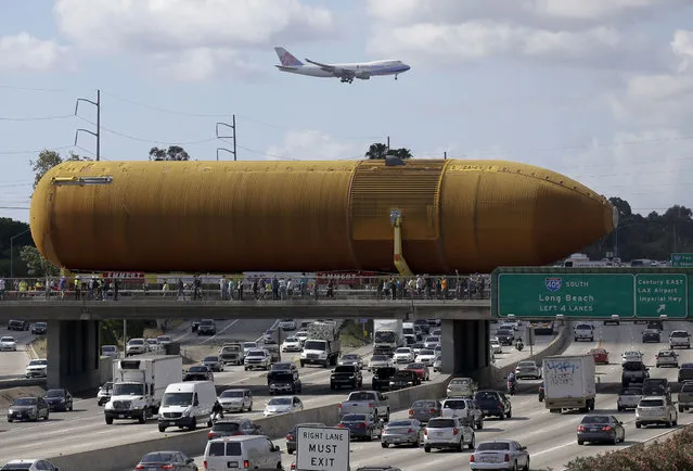 A cargo plane flies overhead as the last remaining space shuttle external propellant tank is moved across the 405 freeway in Los Angeles on Saturday, May 21, 2016. The ET-94 will be displayed with the retired space shuttle Endeavour at the California Science Center. (Photo by Chris Carlson/AP Photo)