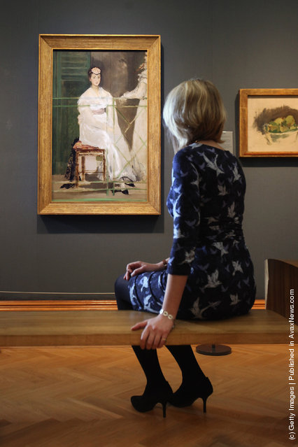 A woman sits near a painting by Edouard Manet entitled 'Portrait of Mademoiselle Claus' from 1868 in the Ashmolean Museum