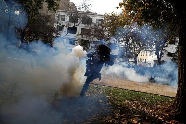 A demonstrator attempts to kick a tear gas canister during an unauthorized march called by secondary students to protest against government education reforms in Santiago, Chile, May 26, 2016. (Photo by Ivan Alvarado/Reuters)