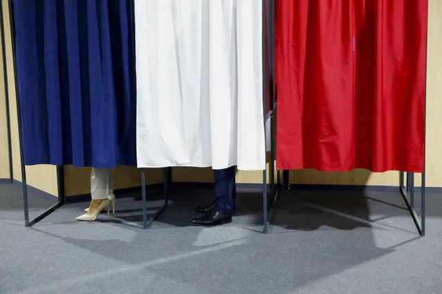 French President and centrist candidate for reelection Emmanuel Macron and his wife Brigitte Macron stand in voting booths at a polling station in Le Touquet, northern France, Sunday, April 24, 2022. France began voting in a presidential runoff election Sunday with repercussions for Europe's future, with centrist incumbent Emmanuel Macron the front-runner but fighting a tough challenge from far-right rival Marine Le Pen. (Photo by Gonzalo Fuentes/Pool via AP Photo)
