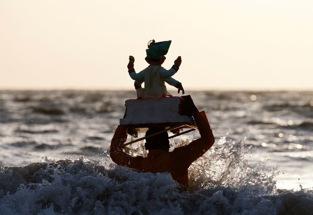 A man carries an idol of the Hindu God Ganesh, the deity of prosperity, for immersion off the coast of the Arabian Sea during the Ganesh Chaturthi festival in Mumbai, India on September 8, 2024. (Photo by Francis Mascarenhas/Reuters)