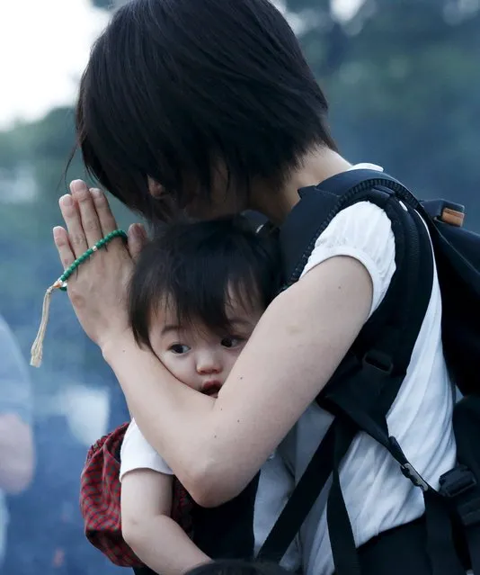 A woman carrying her baby, prays for the atomic bomb victims in front of the cenotaph for the victims of the 1945 atomic bombing, at Peace Memorial Park in Hiroshima, western Japan, August 6, 2015, on the 70th anniversary of the world's first atomic bombing of the city. (Photo by Toru Hanai/Reuters)