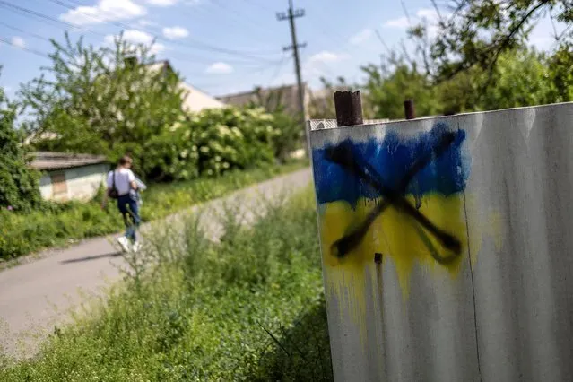 Ukrainian-flag graffiti, painted over with a black cross, is seen at a house fence, amid Russia's invasion of Ukraine, in Pokrovsk, Donetsk region, Ukraine, May 30, 2022. (Photo by Carlos Barria/Reuters)